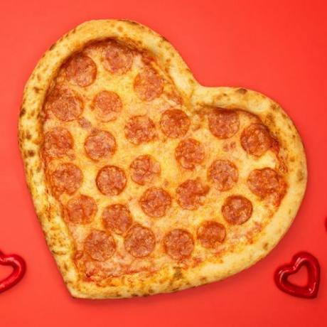 pizza feferoni u obliku srca za dan zaljubljenih na pozadini crvenog papira