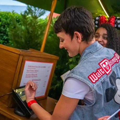 osoba koja nosi čarobnu narukvicu plus u Walt Disney Worldu vrši plaćanje lijepljenjem svoje narukvice na kiosk za plaćanje na pultu