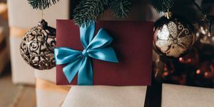 poklon bon u bordo kuverti s plavom mašnom ispod božićnog drvca božićni poklon
